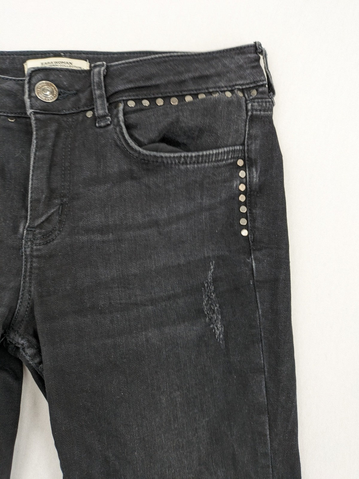 Zara Woman black skinny jeans with distressed details, silver studs, and frayed hem.