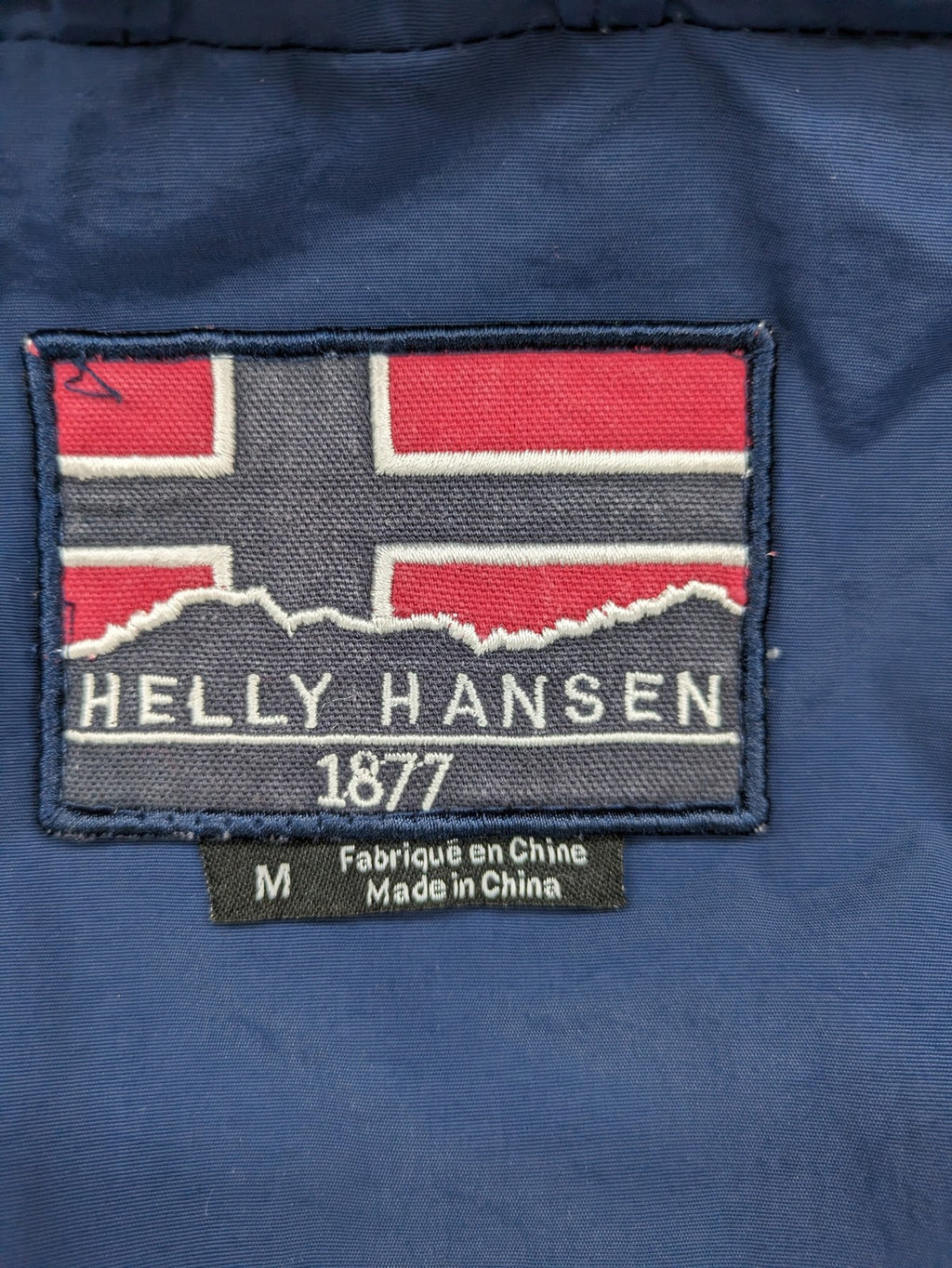 Helly Hansen navy jacket with red accents and logo, full zip, breathable mesh lining.