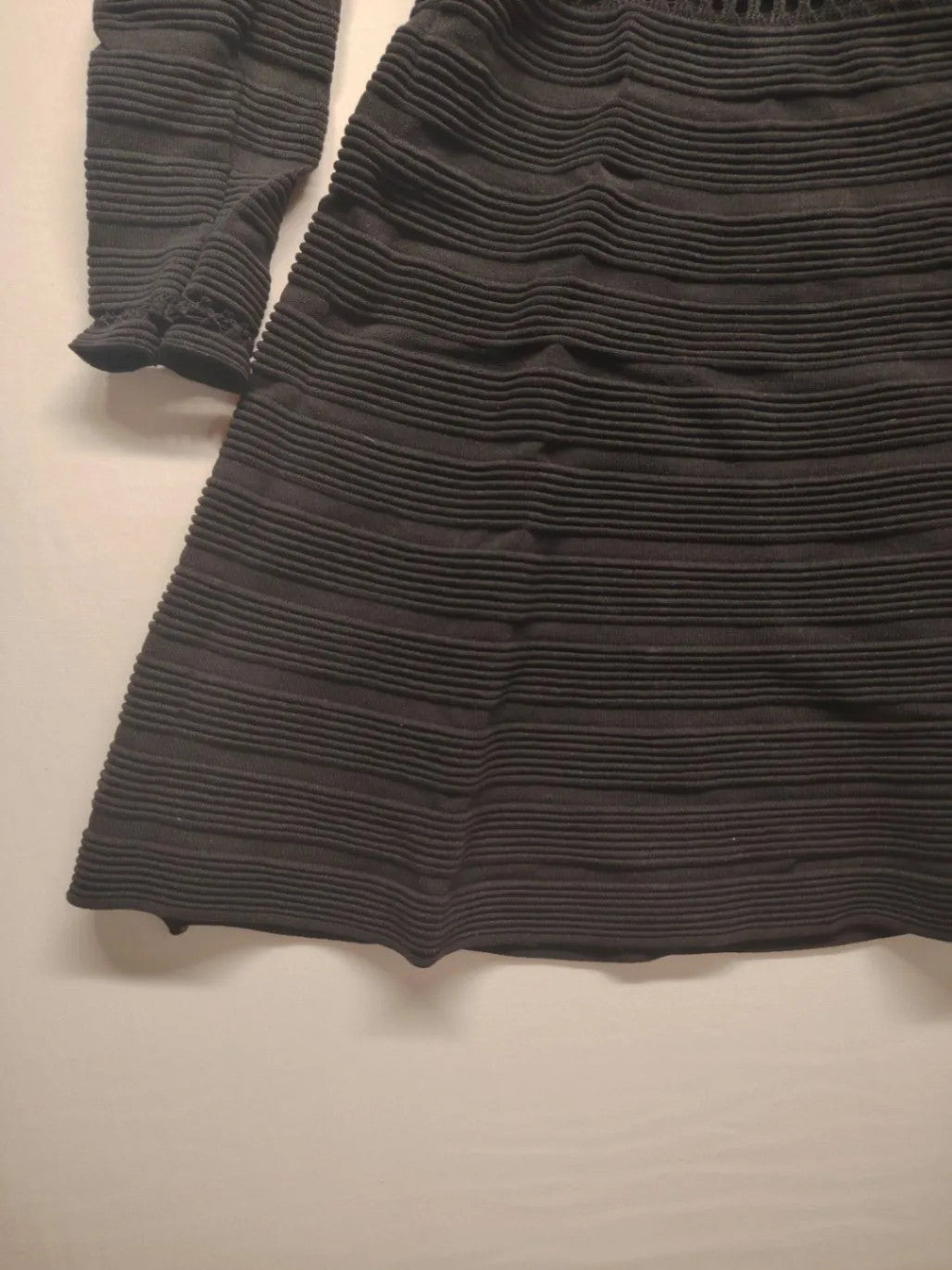 Supertuga black ribbed dress with V-neck, long sleeves, and pointelle detail at waist.