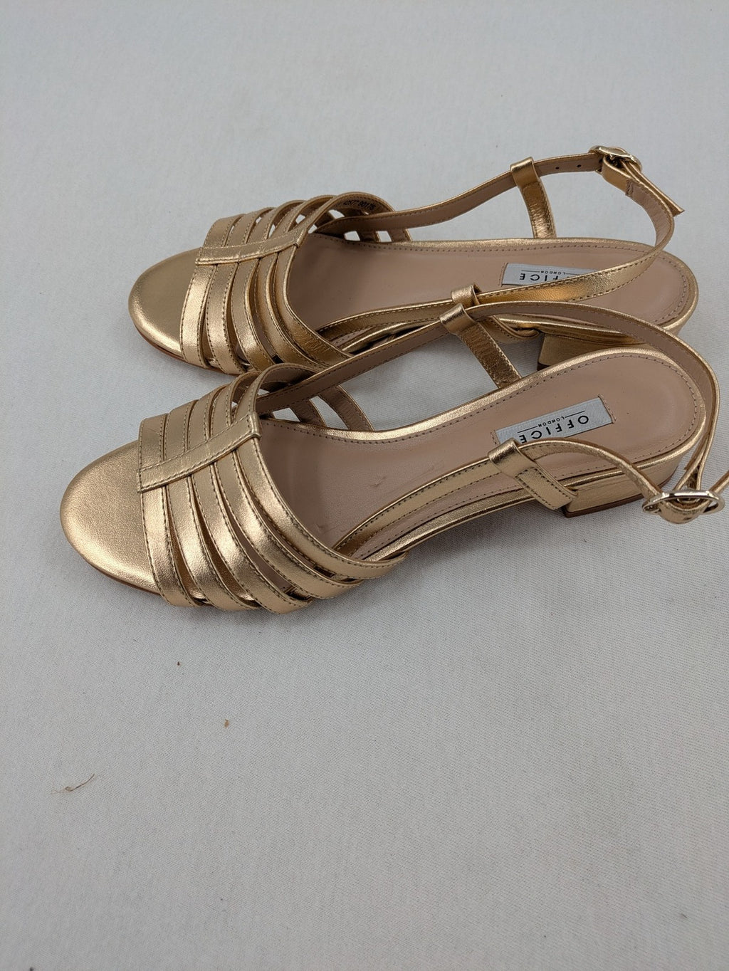 Office London gold metallic sandals with adjustable ankle strap and block heel design.