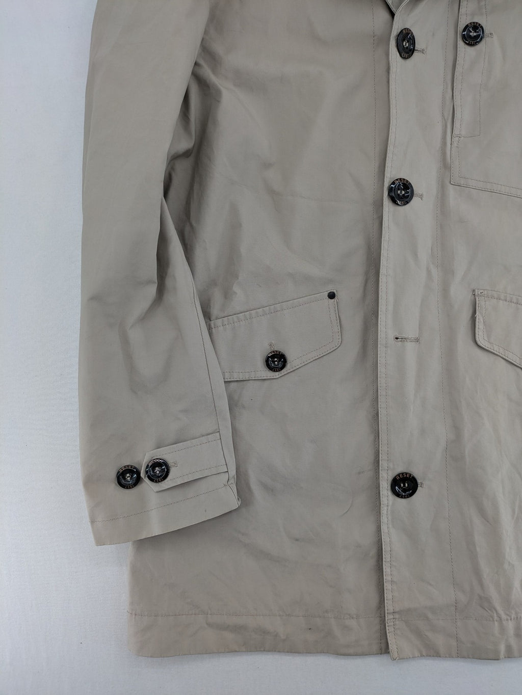ReSET beige coat with contrasting dark blue lining and classic design details.