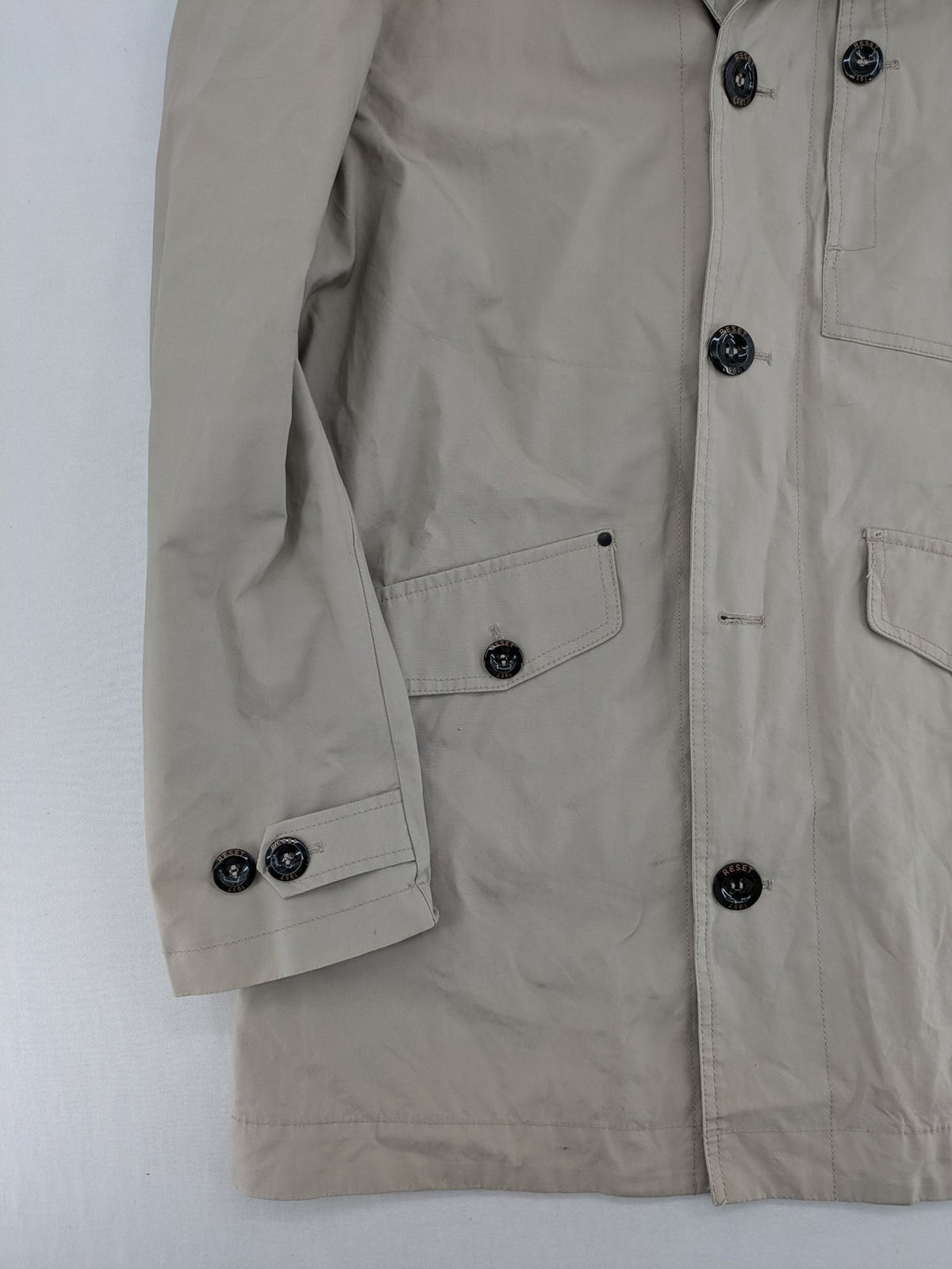 ReSET beige coat with contrasting dark blue lining and classic design details.