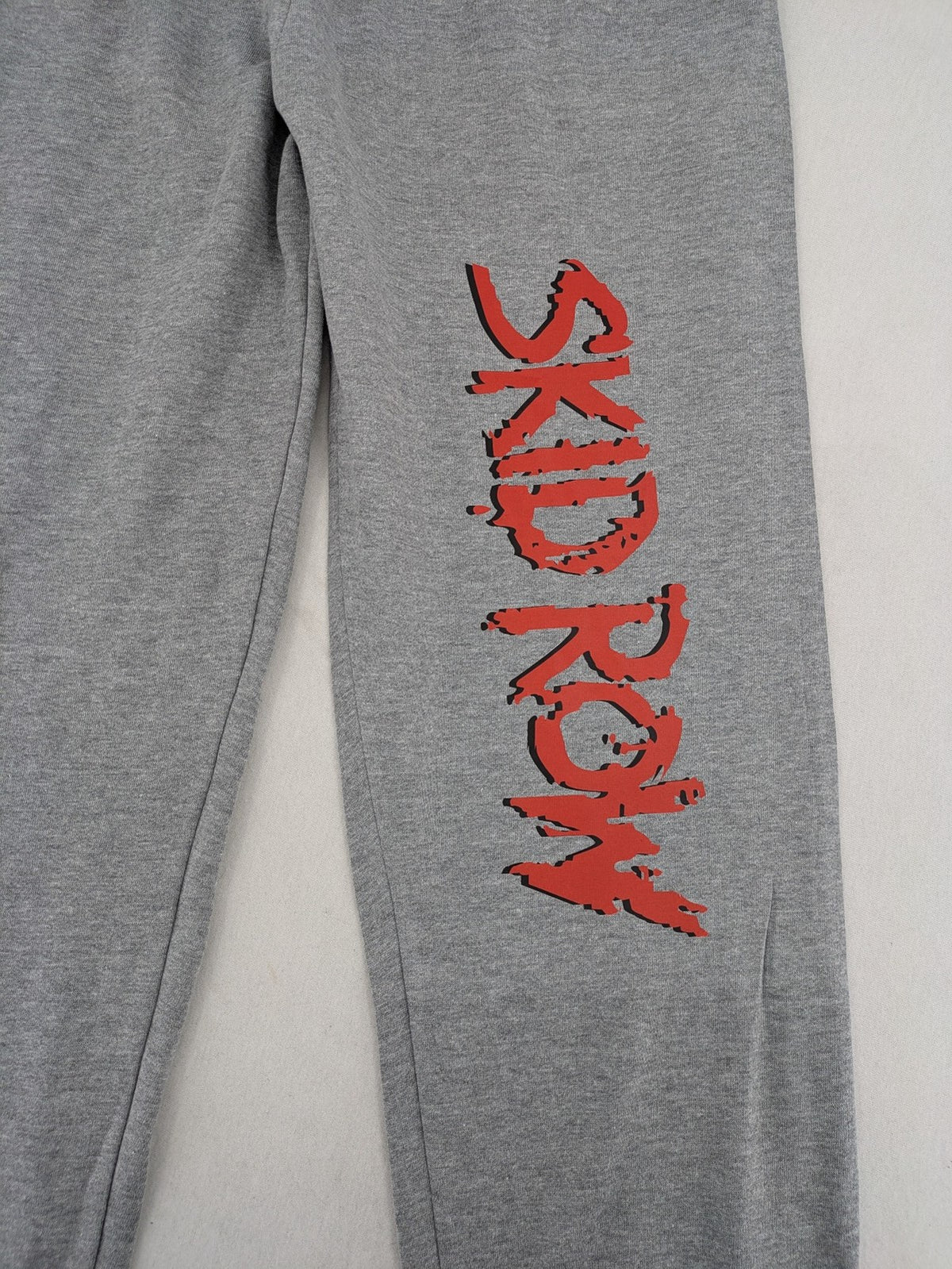 Skid Row grey joggers with red band logo, soft cotton blend, elastic waistband.