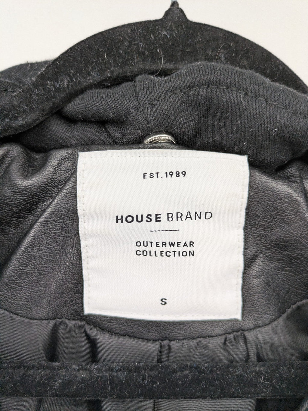 House Brand black biker jacket with hood, asymmetrical zipper, and belt detail.