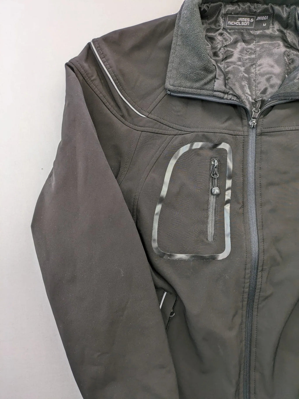 James & Nicholson grey softshell jacket with fleece lining and multiple zip pockets.