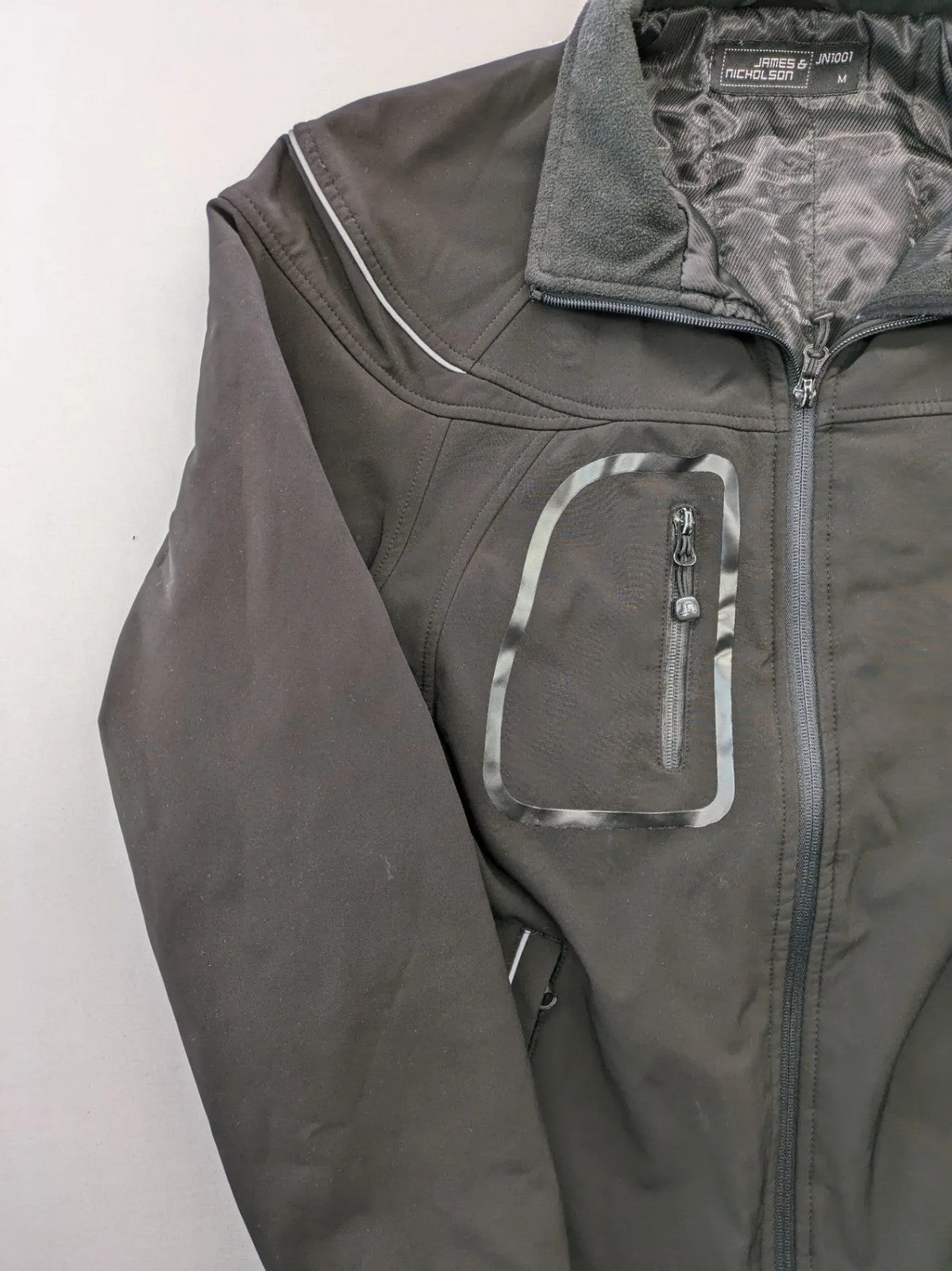James & Nicholson grey softshell jacket with fleece lining and multiple zip pockets.