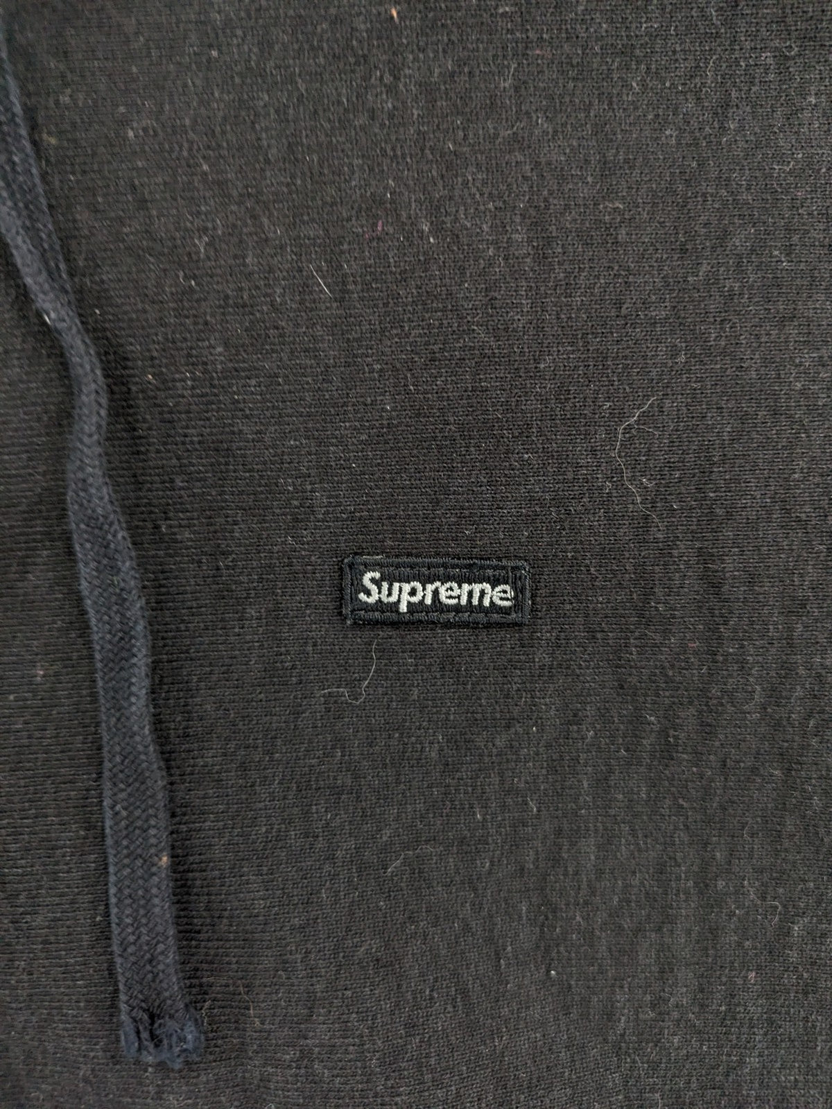 Supreme grey hoodie with embroidered small box logo, kangaroo pocket, and ribbed cuffs.