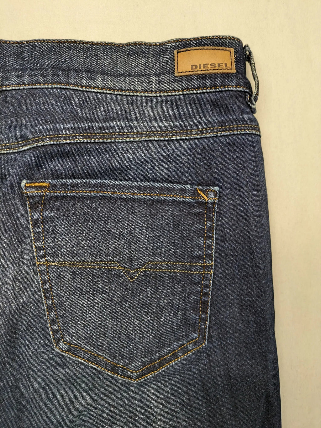Diesel blue straight jeans with regular waist, dark wash, and stretch material.