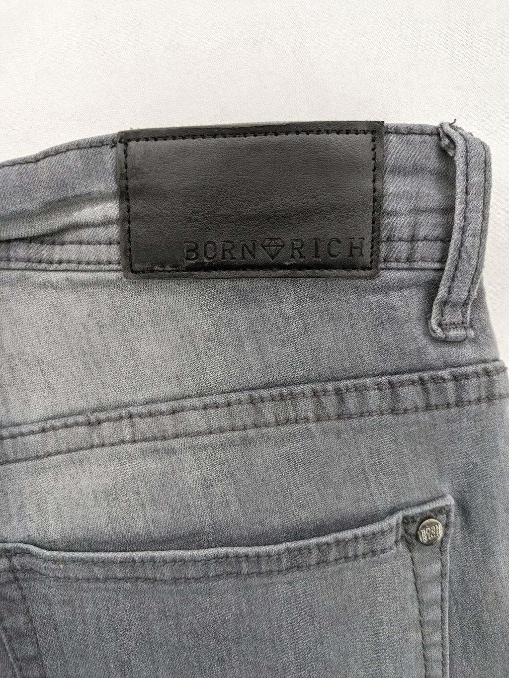 Born Rich grey slim fit jeans with button fly and washed denim texture.