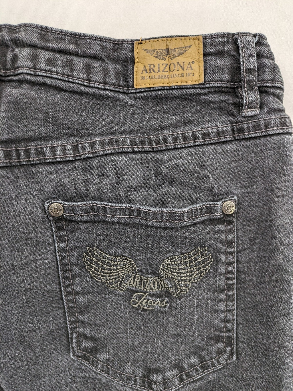 Arizona grey straight jeans with pearl-embellished wing appliqué on back pocket.