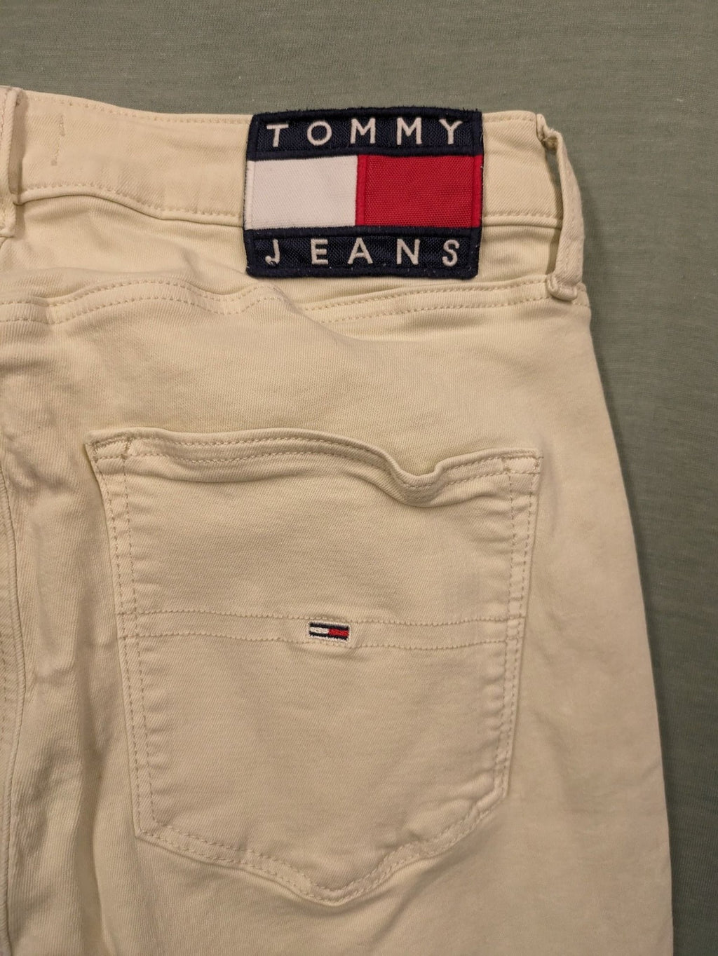 Tommy Jeans beige high rise skinny ankle jeans with logo patch and stretch fabric.