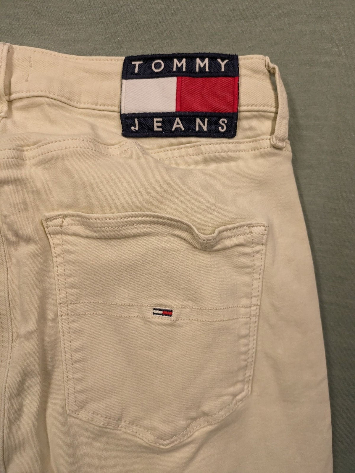 Tommy Jeans beige high rise skinny ankle jeans with logo patch and stretch fabric.