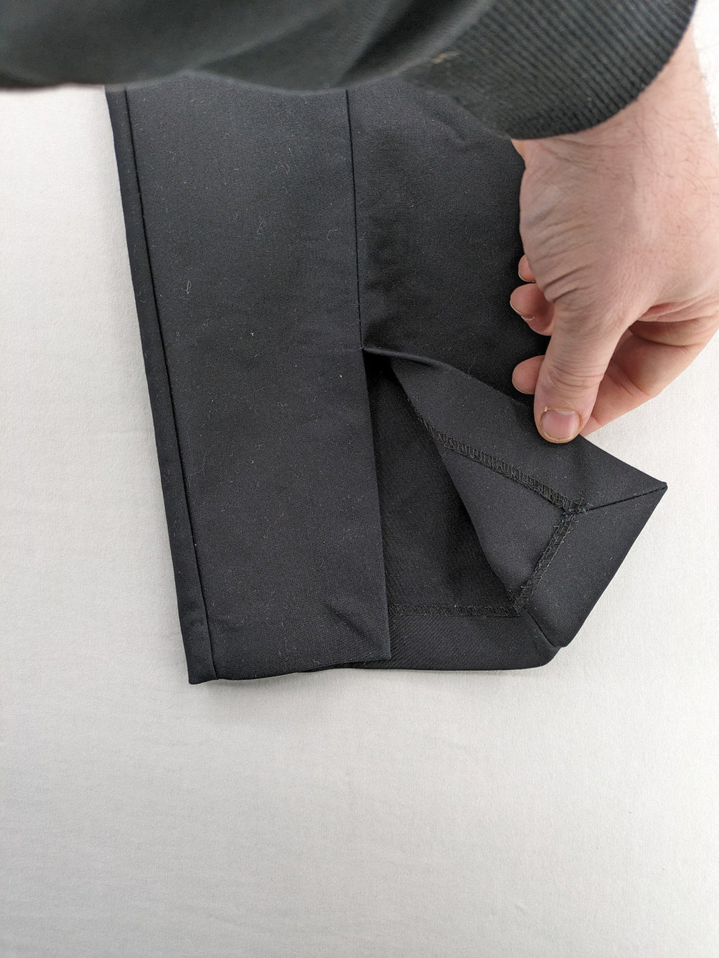 Zara black pants with front creases, subtle slit hem, and buttoned back pocket.