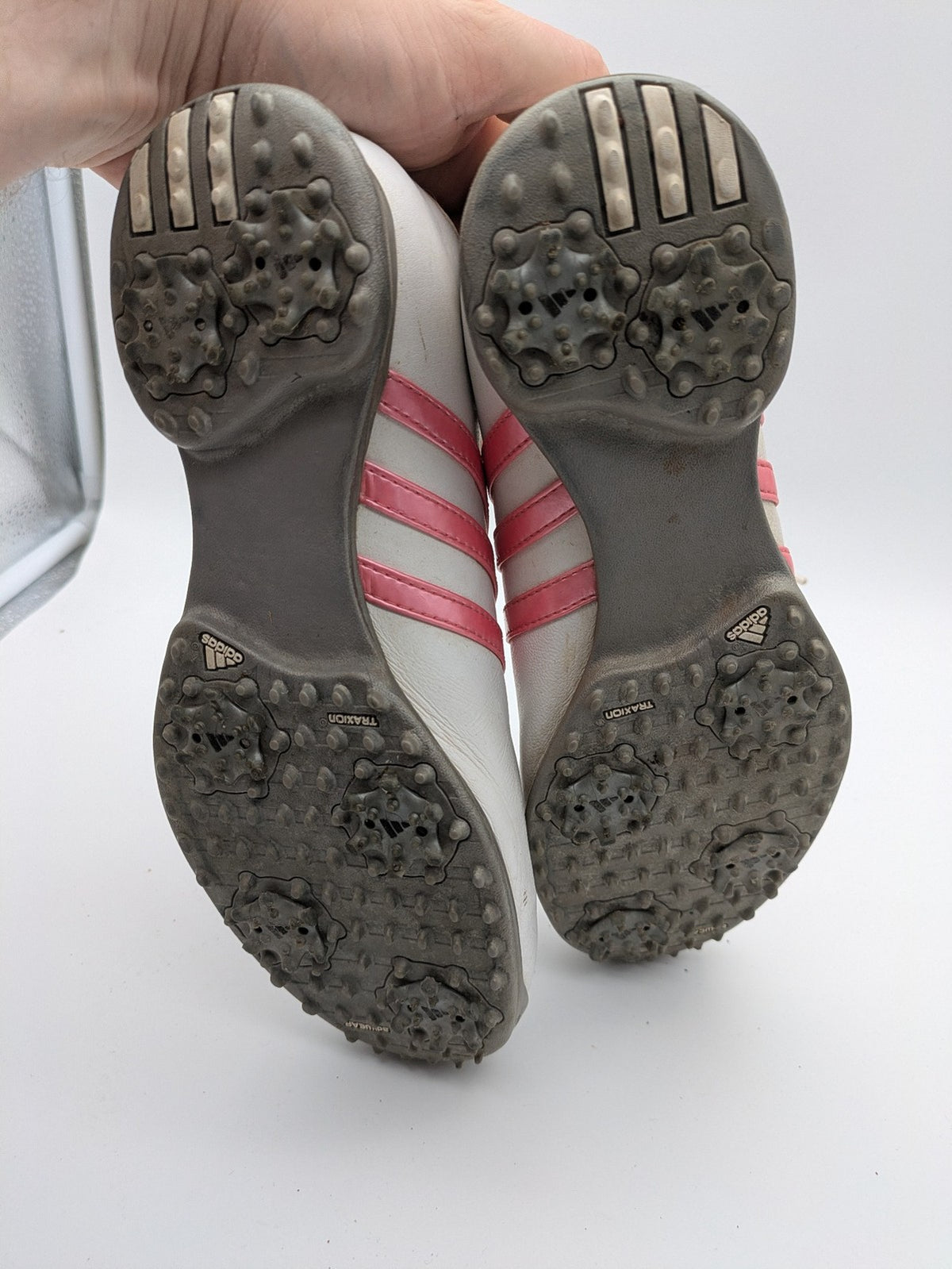 Adidas white golf shoes with pink stripes, Thintech and TRAXION technology, stylish design.