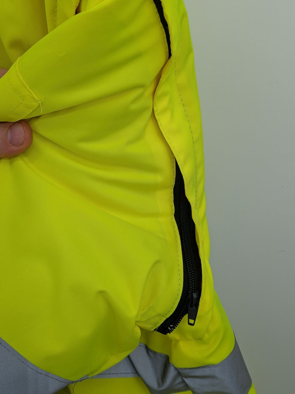 Hüren OHG grey and neon yellow safety jacket with reflective stripes and zippered arm pocket.