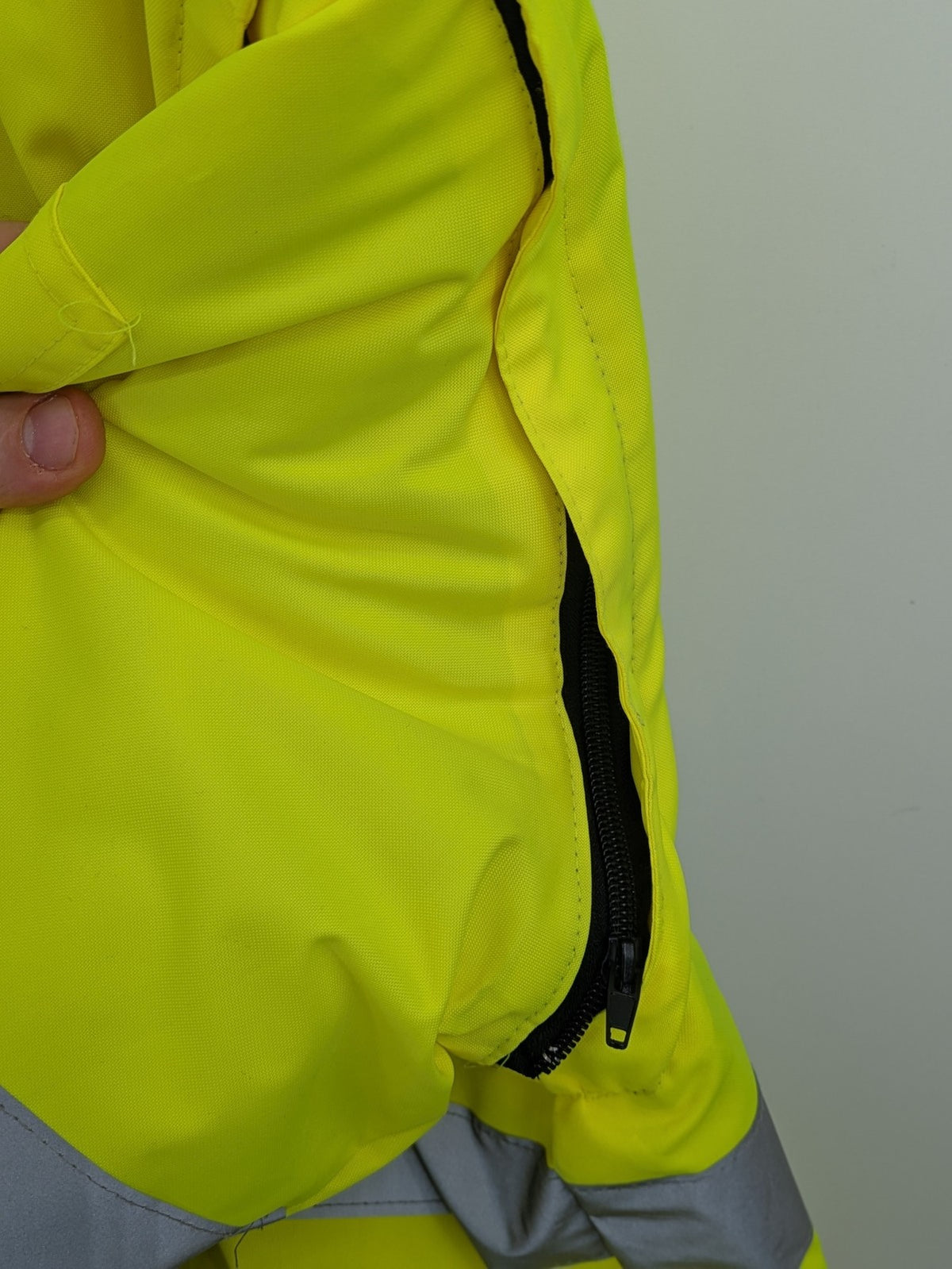 Hüren OHG grey and neon yellow safety jacket with reflective stripes and zippered arm pocket.