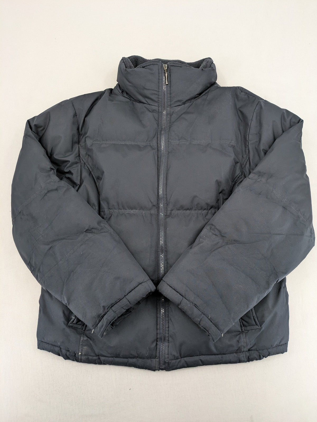 Identic black puffer jacket with quilted design and fleece-lined high collar.