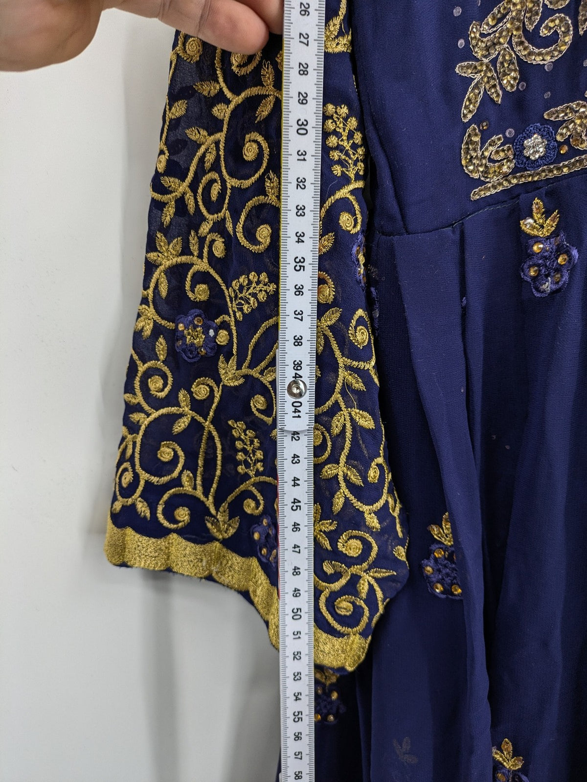 Bollywood bridal party dress gold with intricate blue embroidery and flowing Anarkali silhouette.