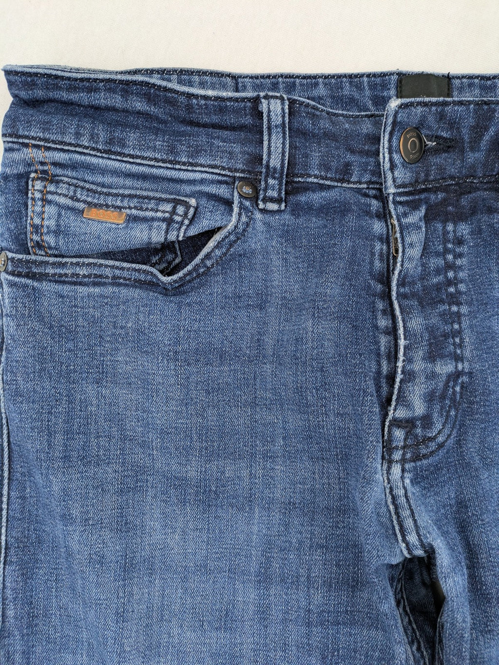 BOSS blue slim fit jeans with logo, five-pocket design, and button fly.