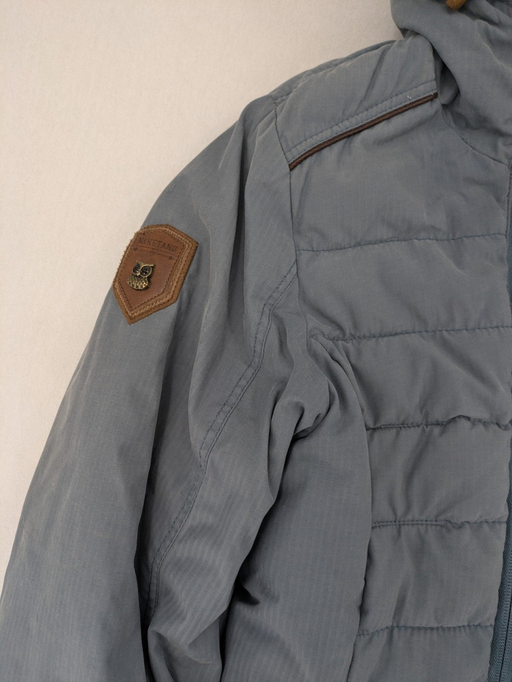 Naketano blue jacket with teddy fleece lining, hood, and leather appliqués.