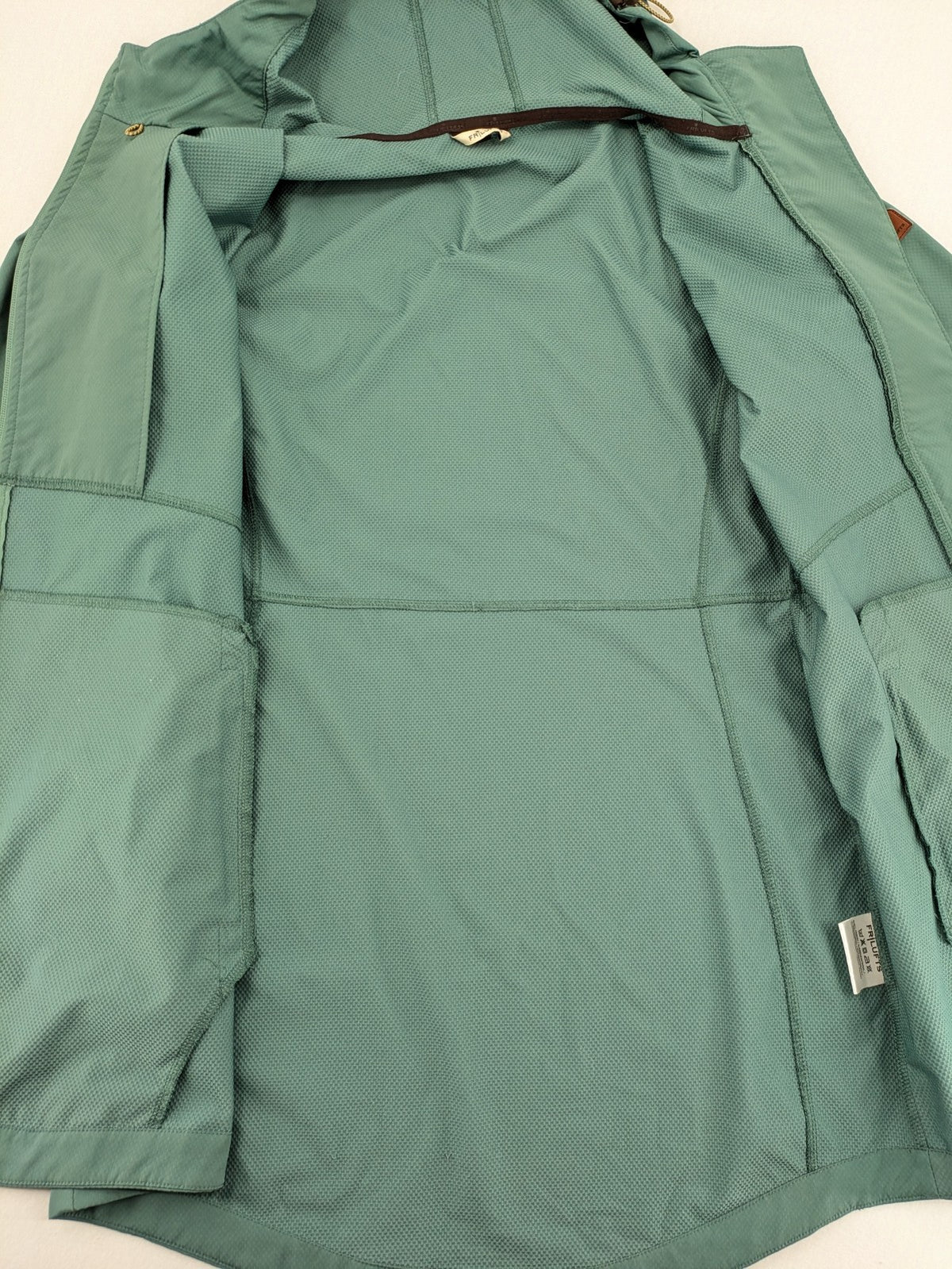 Frilufts green softshell jacket with hood, longline design, durable zipper, practical zip pockets.