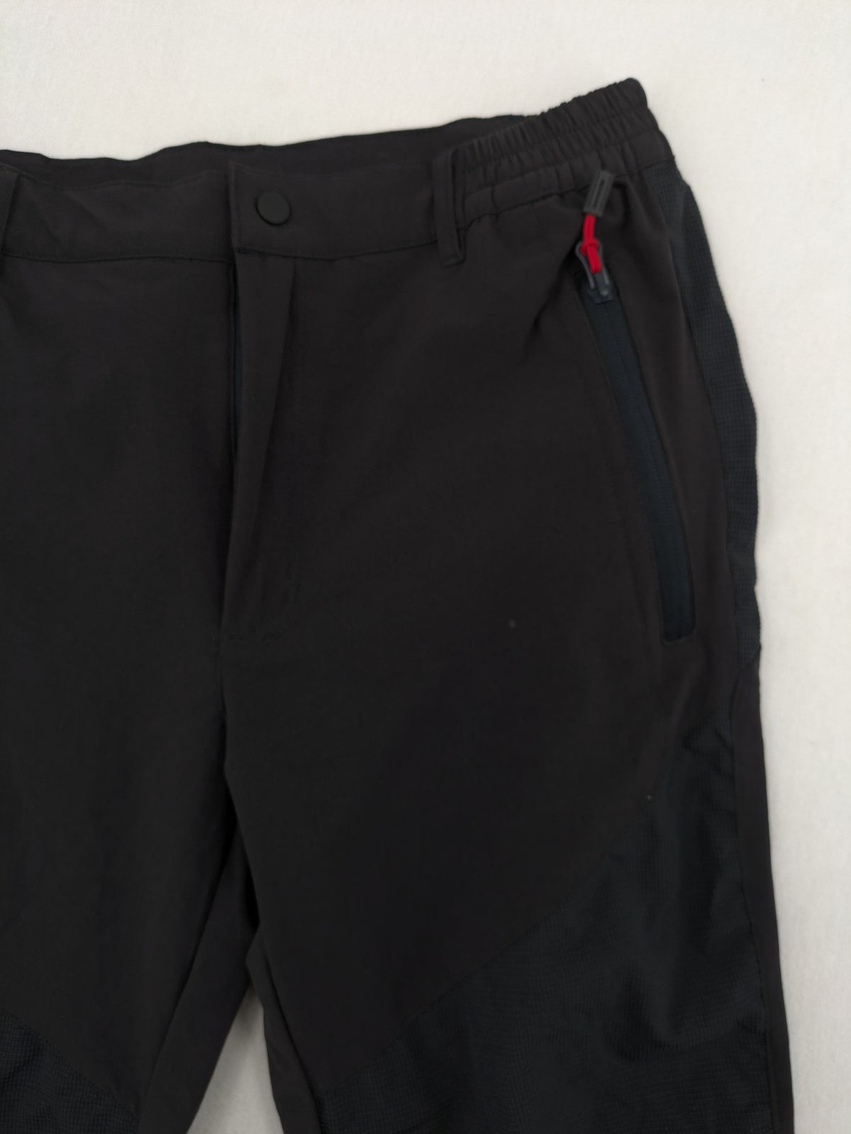 Outdoor black capri pants with elastic waistband and multiple zippered pockets.
