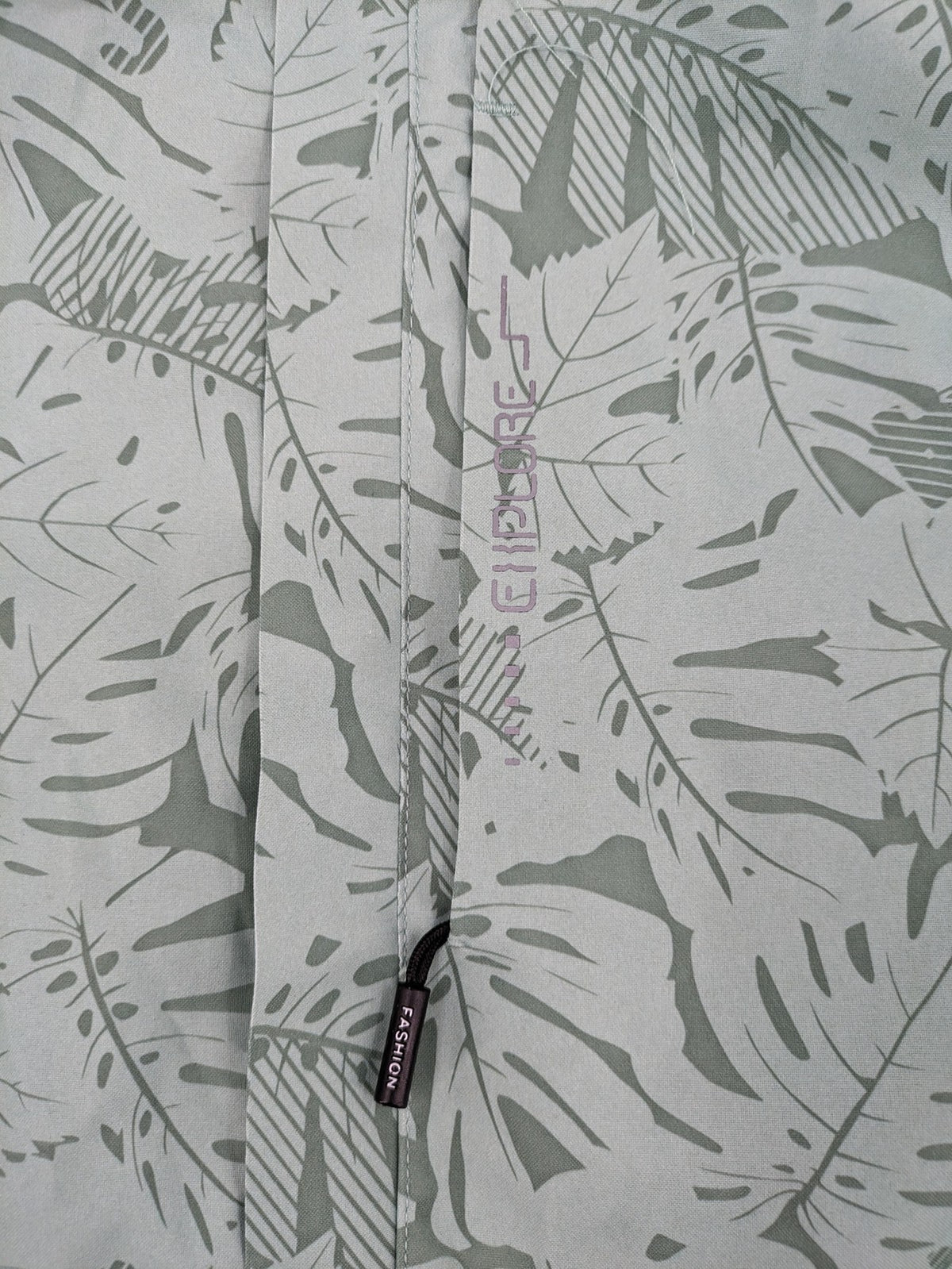 Outdoor green jacket with allover leaf print, adjustable hood, and front zipper.