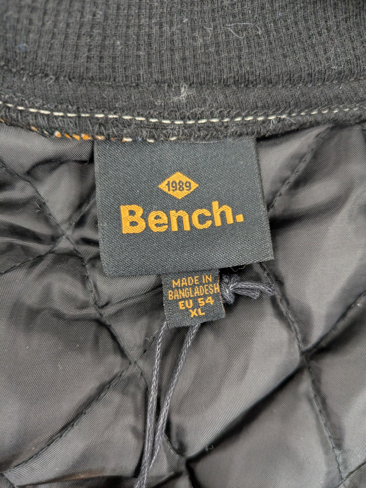 Bench cream flannel jacket with check pattern, black hood, and button placket.