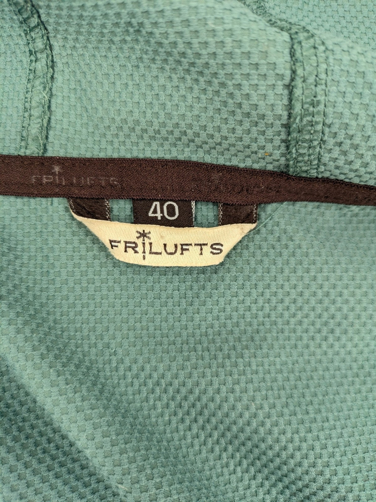 Frilufts green softshell jacket with hood, longline design, durable zipper, practical zip pockets.