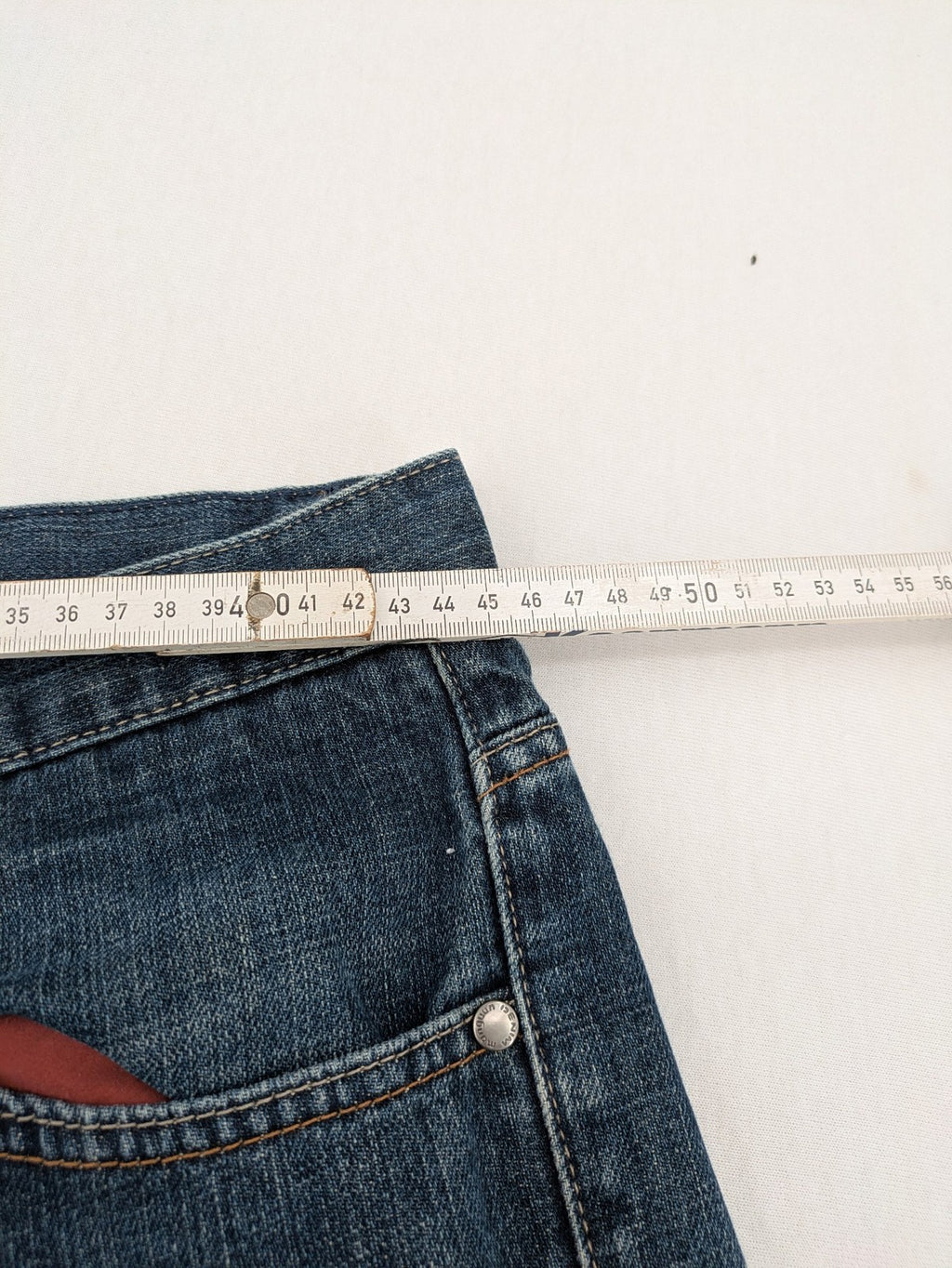 Indygo blue straight jeans 5-pocket style with subtle red pocket detail, cotton material.