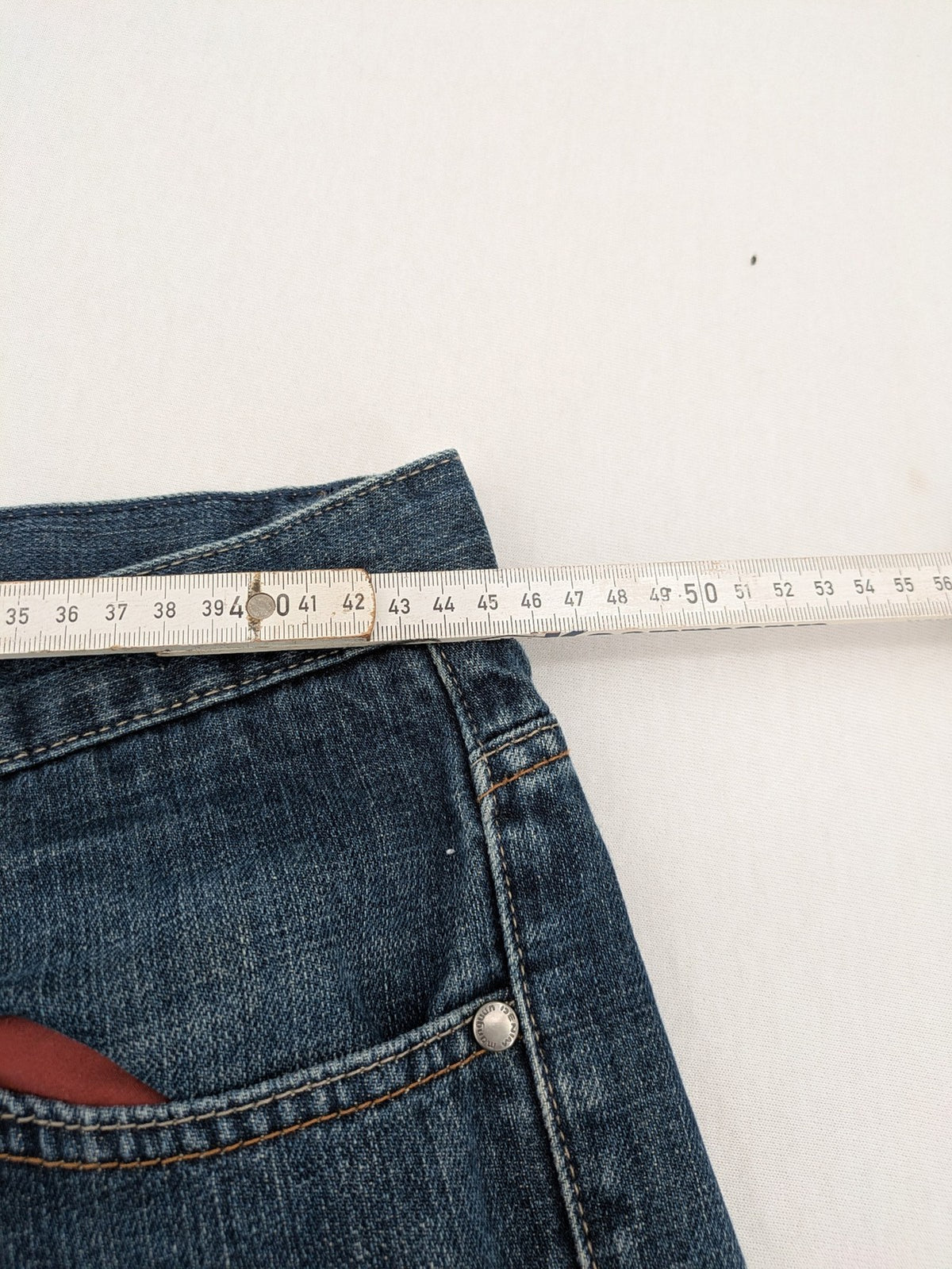 Indygo blue straight jeans 5-pocket style with subtle red pocket detail, cotton material.