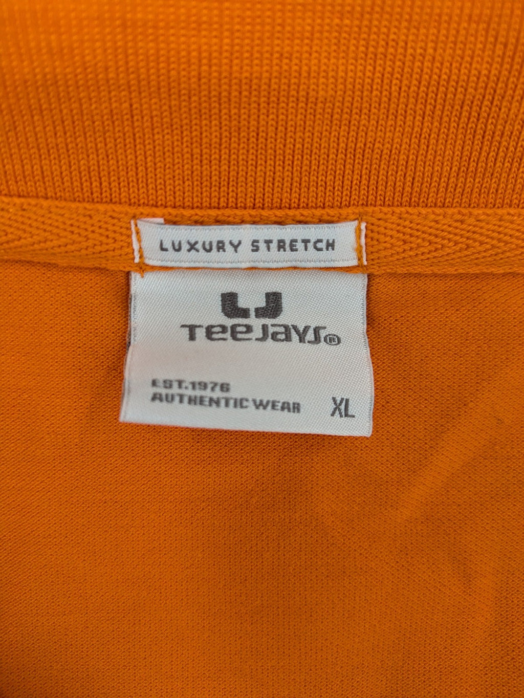 Teejays orange polo shirt with embroidered logo, classic collar, and button placket.