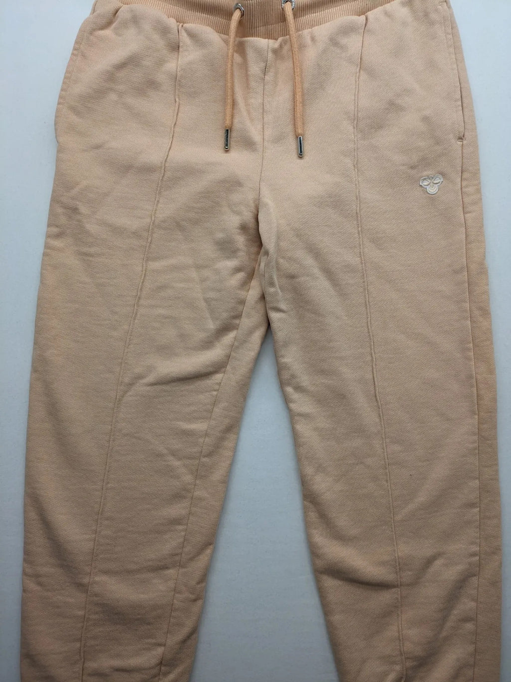 Hummel beige jogging pants with adjustable drawstring, embroidered logo, and ankle cuffs.