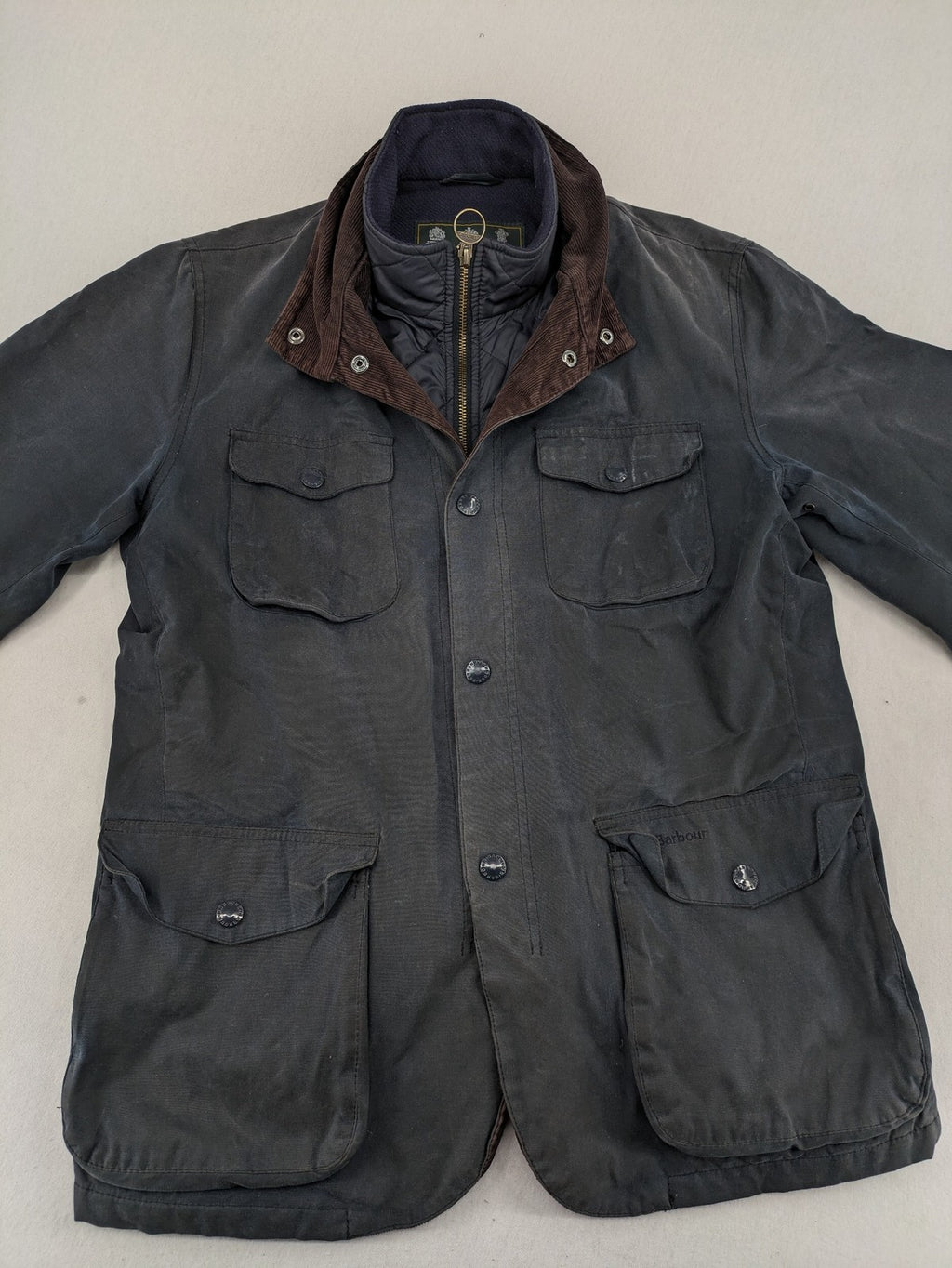 Barbour navy wax jacket with quilted lining and leather elbow patches, tartan interior.