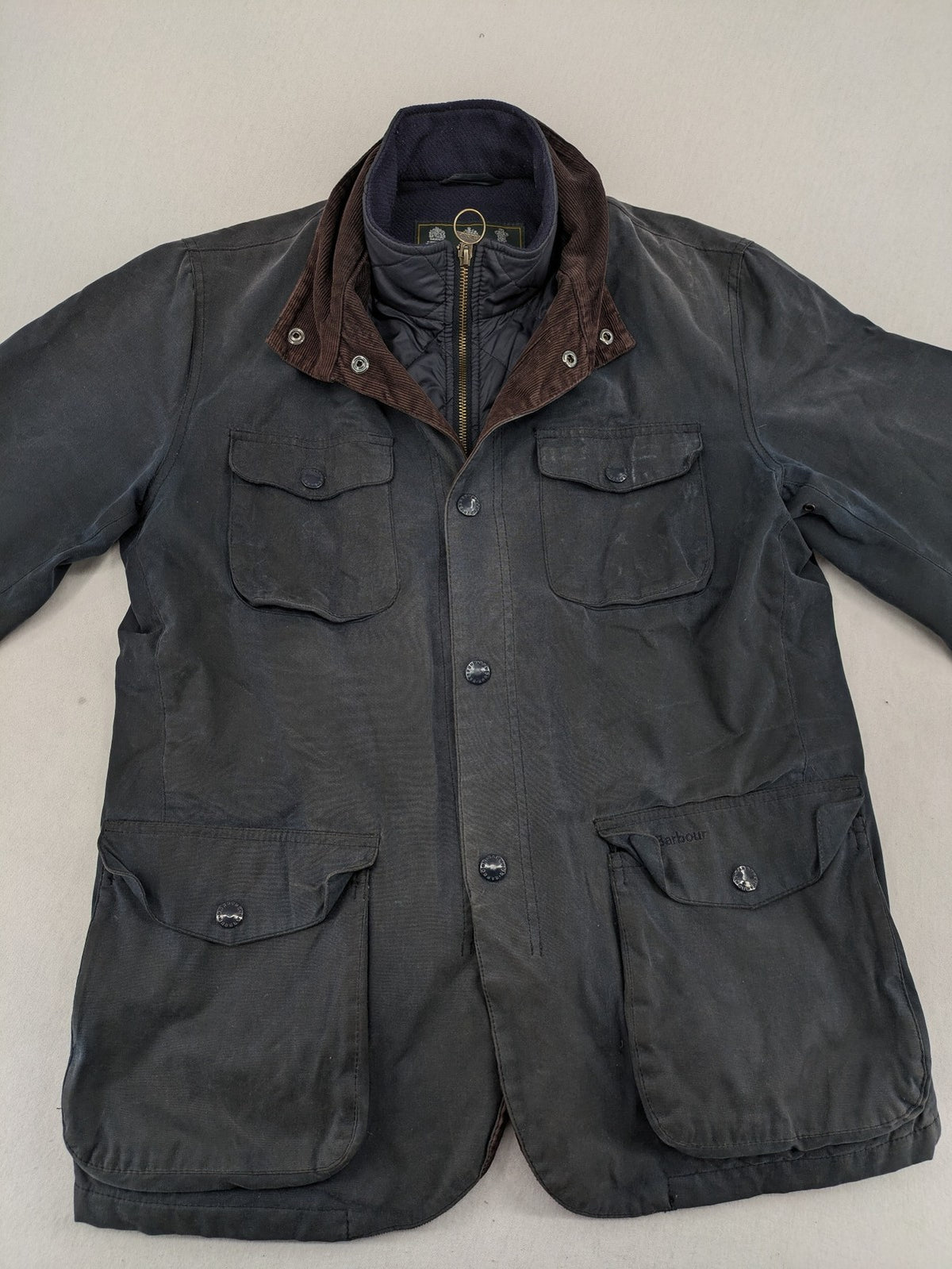 Barbour navy wax jacket with quilted lining and leather elbow patches, tartan interior.