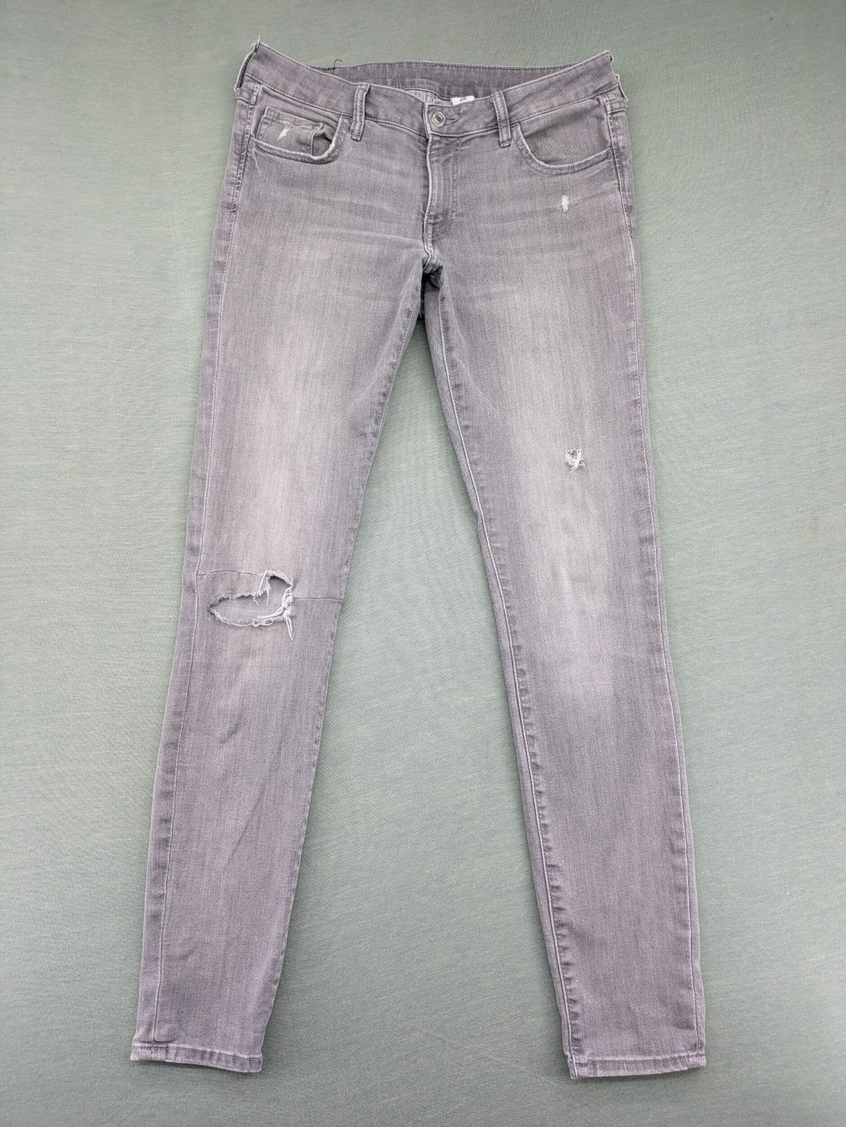H&M grey super skinny jeans with distressed knee details and low waist fit.