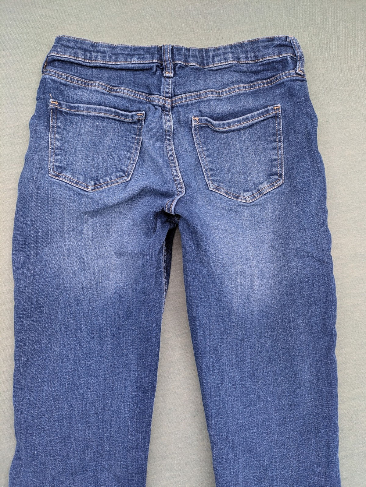 H&M blue skinny jeans with distressed knee details and classic 5-pocket design.