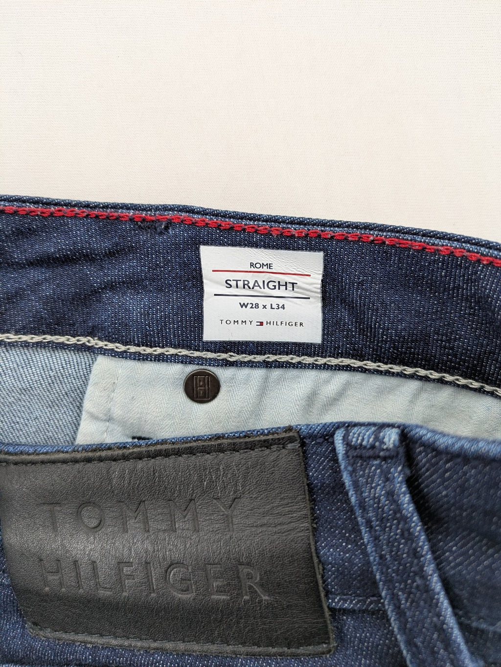 Tommy Hilfiger blue straight jeans with iconic logo and dark wash denim finish.