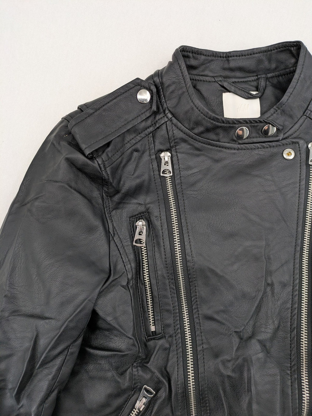 H&M black biker jacket with silver zippers, shoulder flaps, and snap-button details.