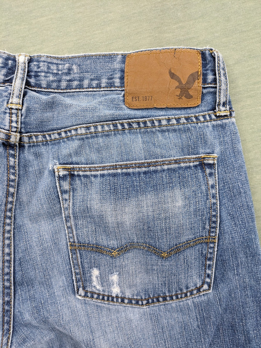 American Eagle Outfitters blue straight jeans with distressed detailing and classic five-pocket design.