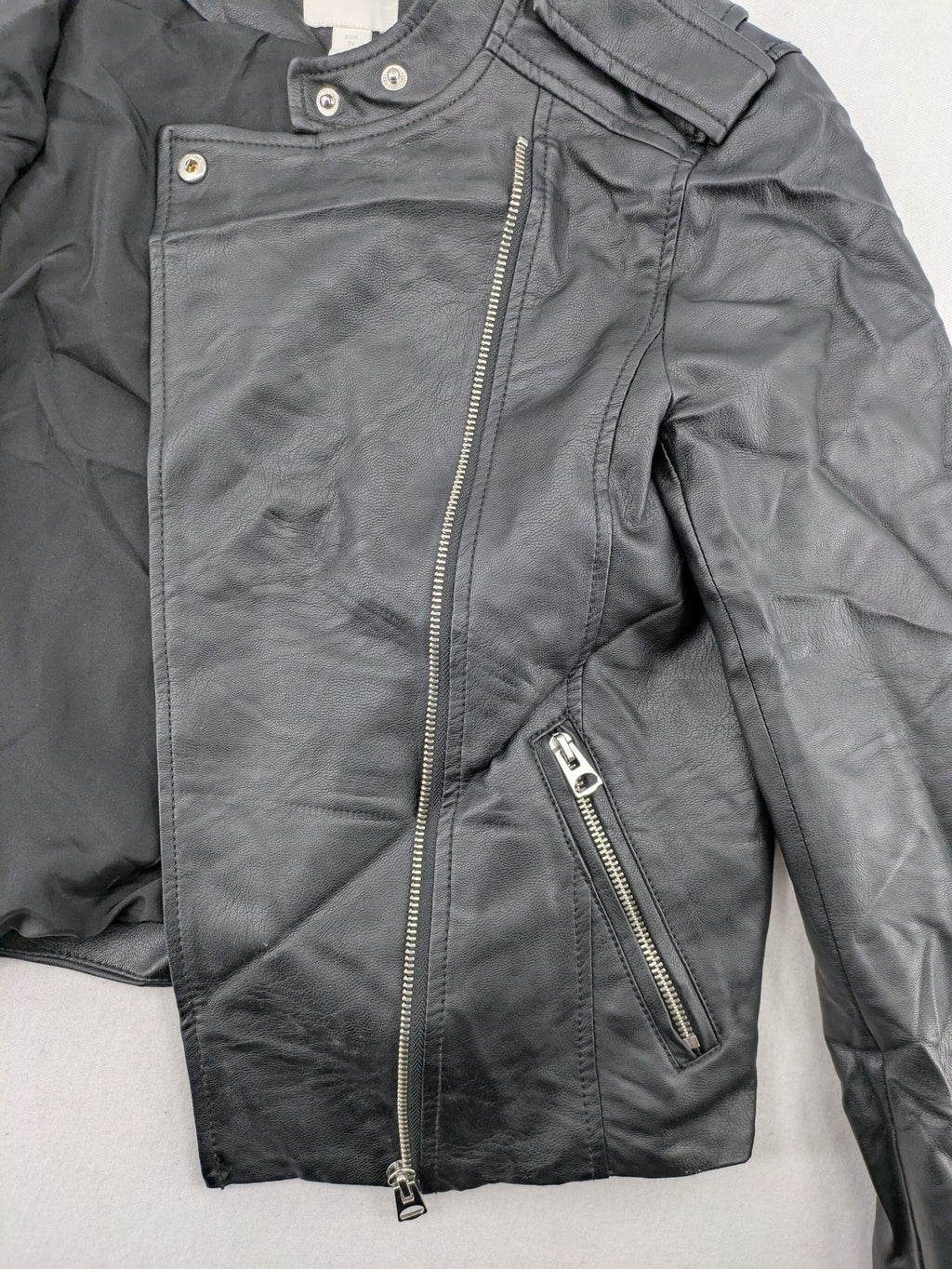 H&M black biker jacket with silver zippers, shoulder flaps, and snap-button details.