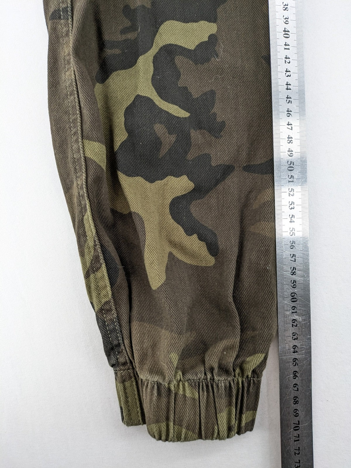 Rainbow camouflage cargo pants in green-brown with jogger silhouette and multiple pockets.