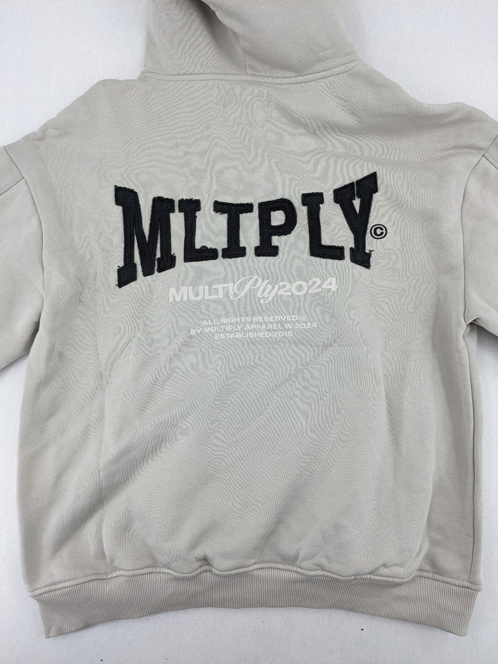 Multiply grey zip-through hoodie with embroidered logo and large "MLTPLY" print on back.