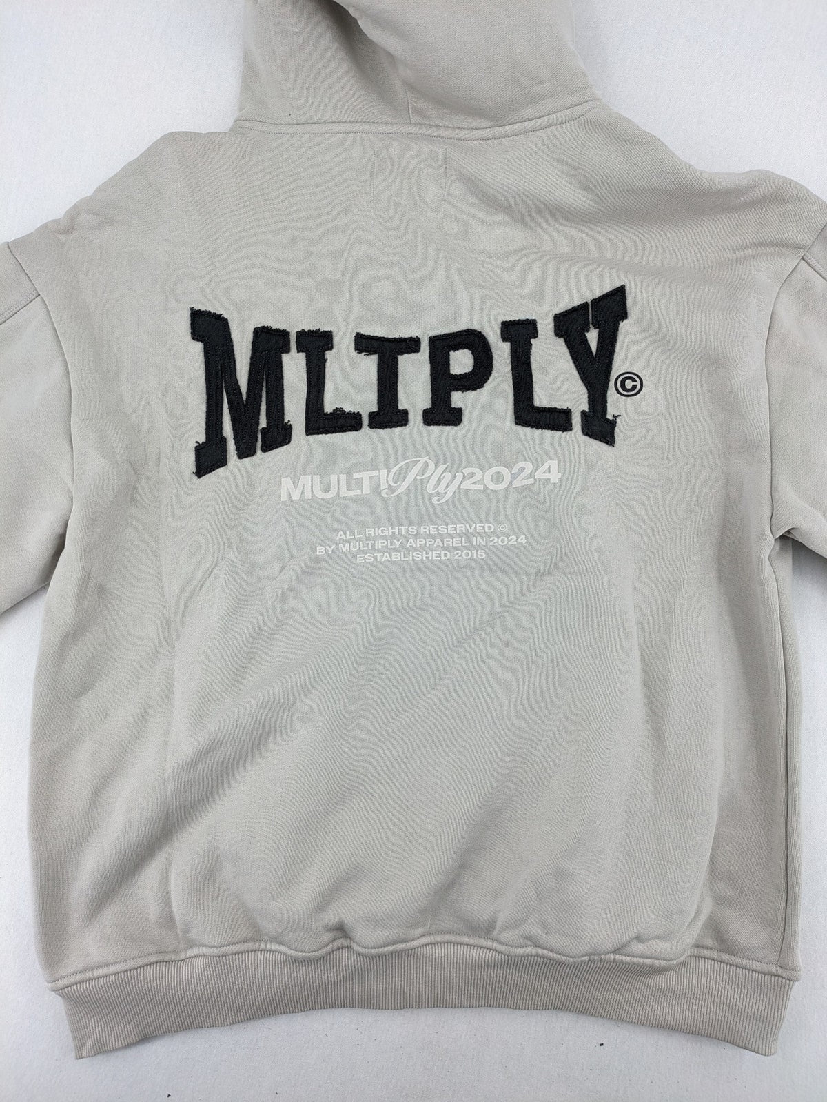 Multiply grey zip-through hoodie with embroidered logo and large "MLTPLY" print on back.