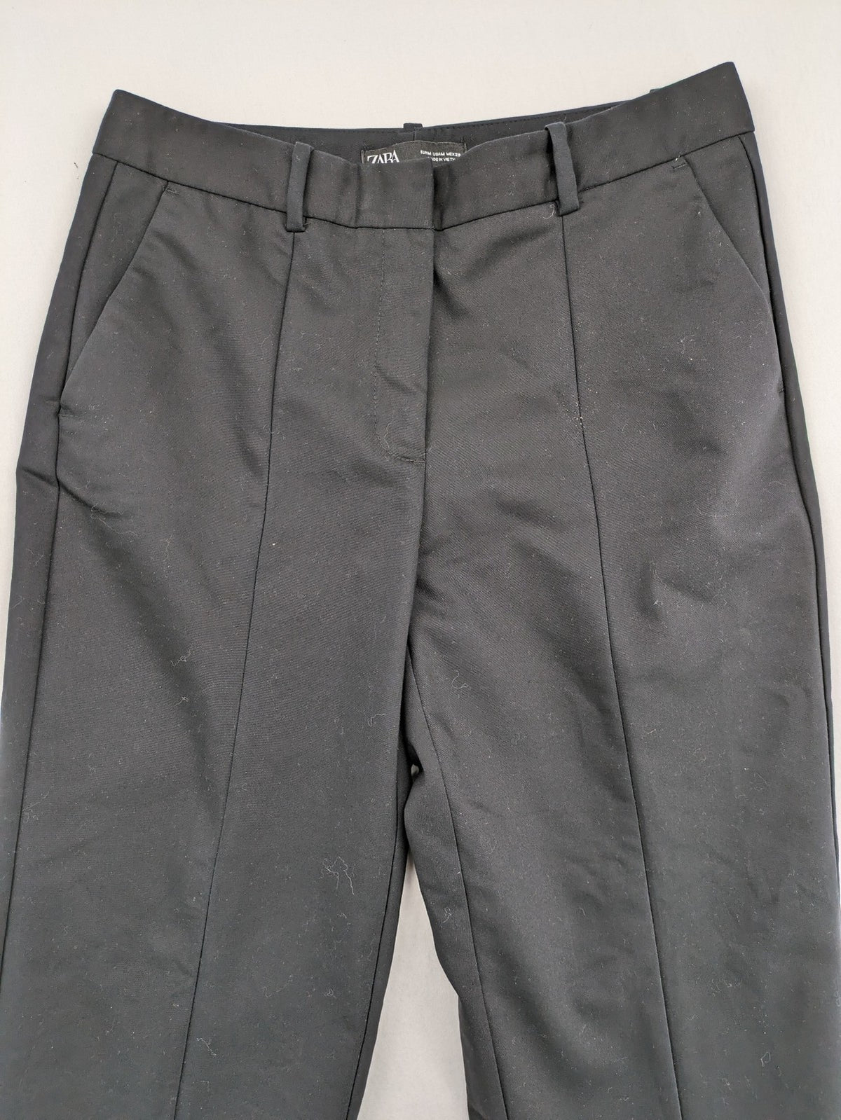 Zara black pants with front creases, subtle slit hem, and buttoned back pocket.