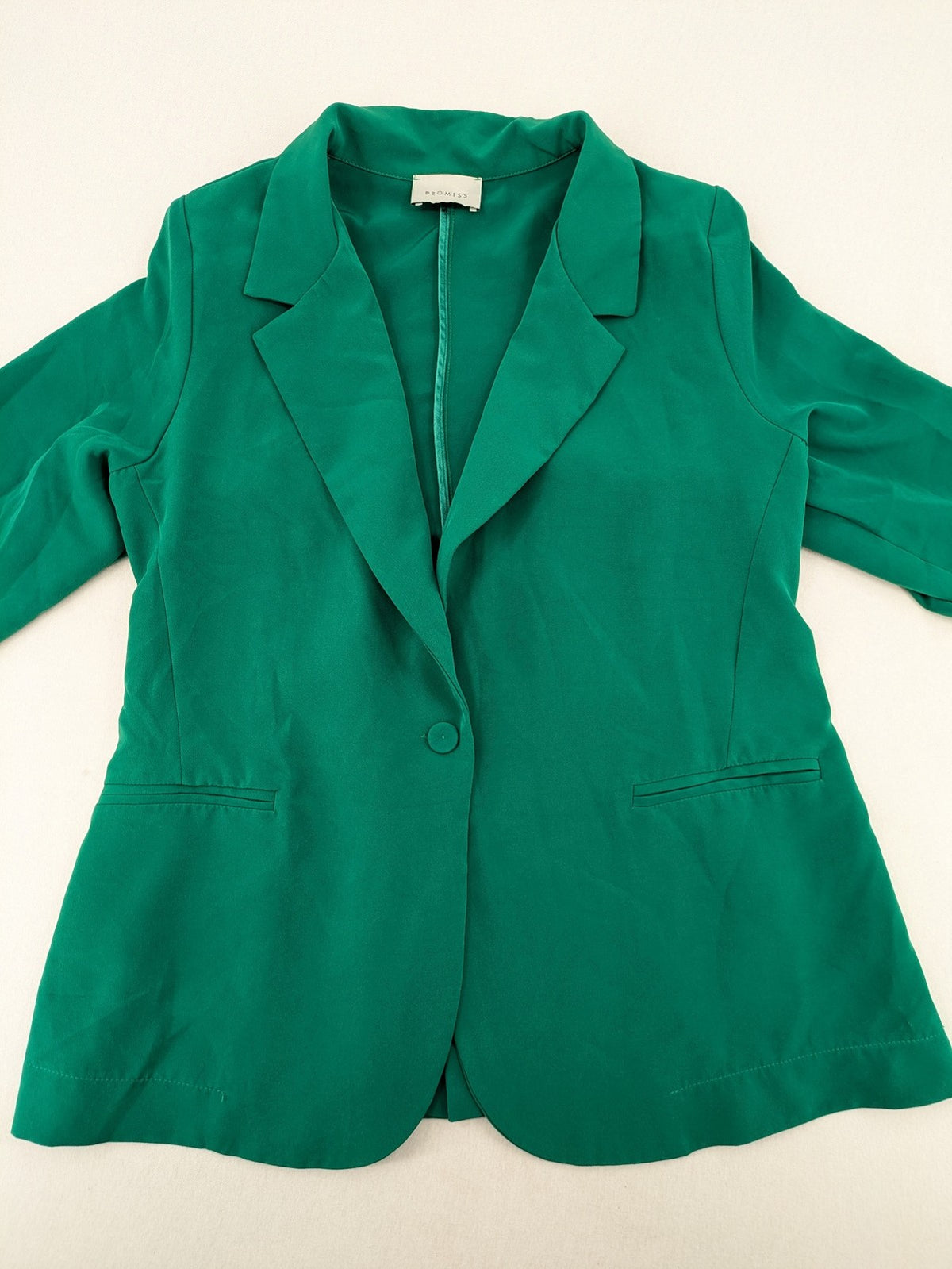 Promiss green blazer jacket single-button design with notch lapels and decorative pockets.