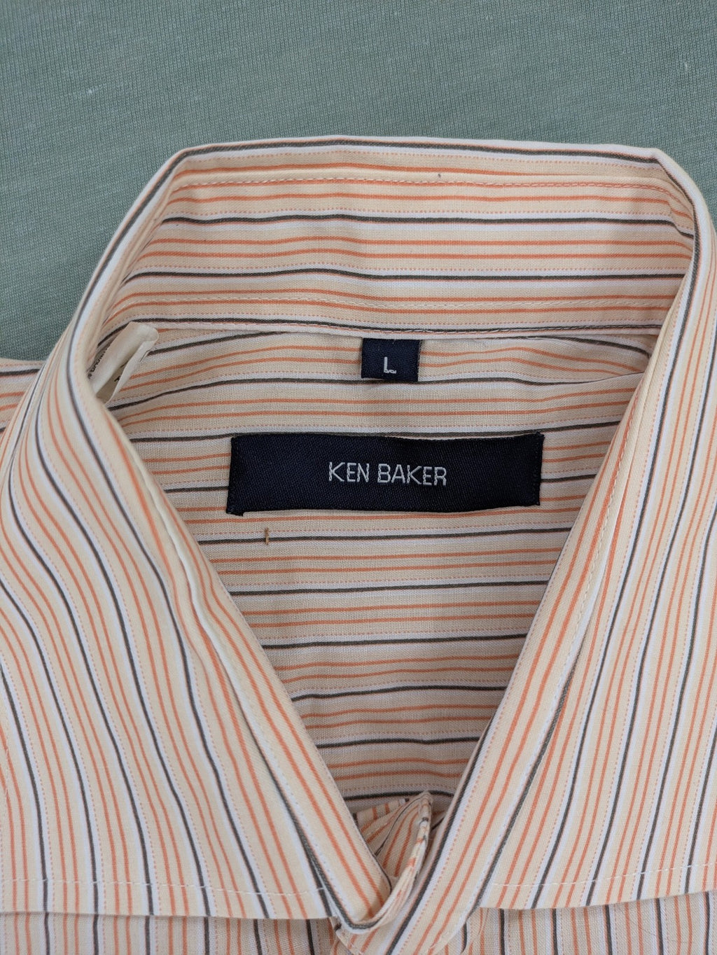 Ken Baker orange short-sleeve shirt with vertical stripes and chest pocket.