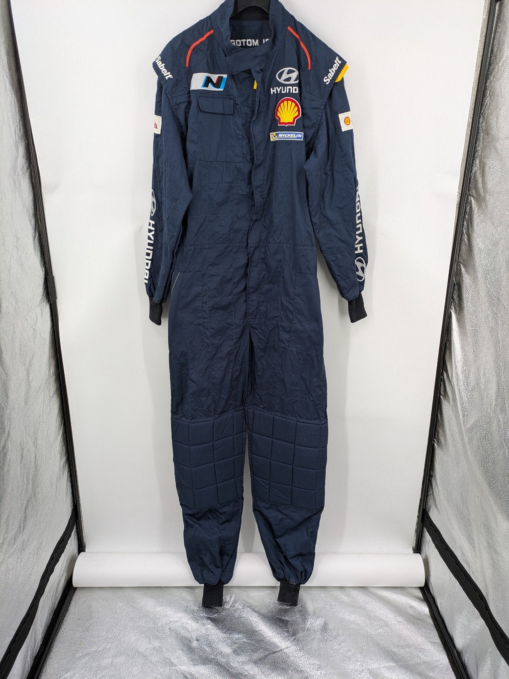 Hyundai Motorsport Sabelt racing suit navy blue with embroidered Shell and Michelin logos.