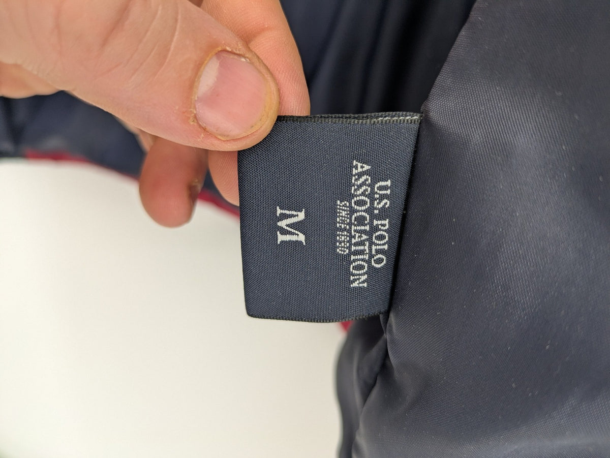 US Polo Assn. puffer jacket navy red two-tone design with embroidered logo and zip pockets.