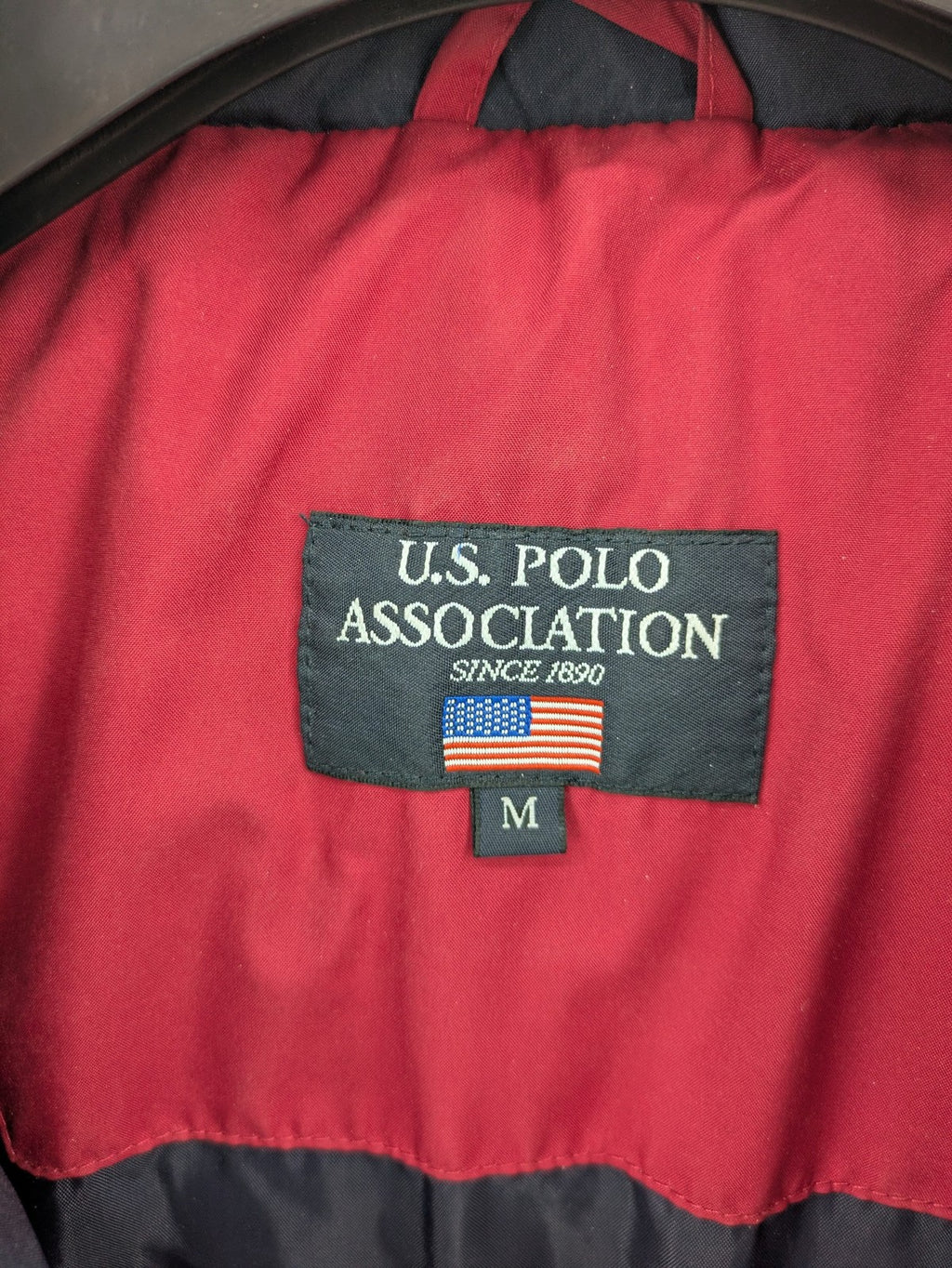 US Polo Assn. puffer jacket navy red two-tone design with embroidered logo and zip pockets.